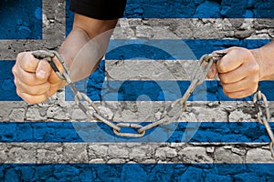 Male hands break the iron chain, a symbol of bondage,protest against the background of the national flag of Greece, the concept of