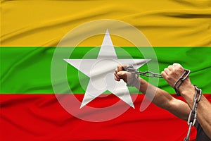 Male hands break the iron chain, a symbol of tyranny, protest against the background of the national flag of Myanmar, the concept