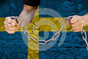 Male hands breaking the iron chain, symbol of tyranny, protest against the background of the national flag of Sweden, the concept