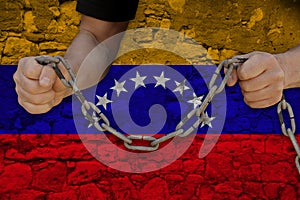 Male hands breaking the iron chain, symbol of tyranny, protest against the background of the Venezuela state flag, the concept of