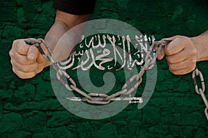 Male hands breaking iron chain, symbol of tyranny, protest against of national flag kingdom of saudi arabia with Arabic