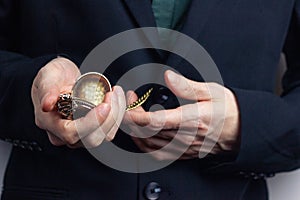 Male hands of a businessman in a business suit with a ring on his finger hold a pocket old time. Horizontal orientation photo, bus