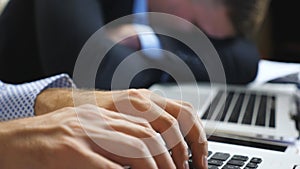 Male hands of businessman typing text on laptop keyboard at office. Arms of young manager working on notebook indoor