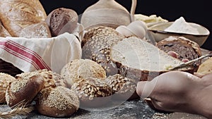 Male hands butter a piece of fresh baked Dutch bread above the wooden table