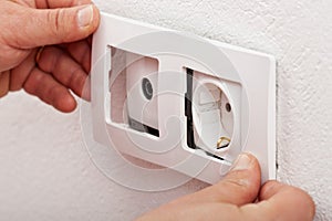 Male hands changing an electical wall outlet