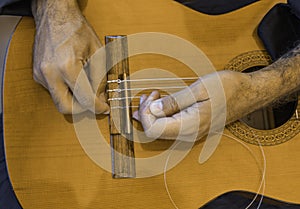 Male hands changing the strings of a classical guitar