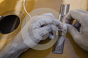 Male hands changing the strings of a classical guitar