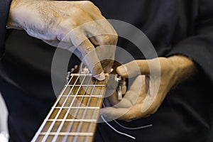 Male hands changing the strings of a classical guitar