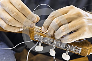 Male hands changing the strings of a classical guitar