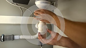 Male hands checking clogged water pipes, repairing plumbing leaks, closeup