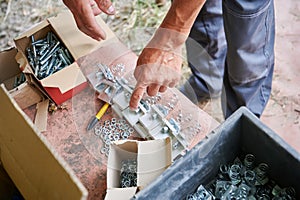 Male hands choosing bolts and channel nuts with springs.