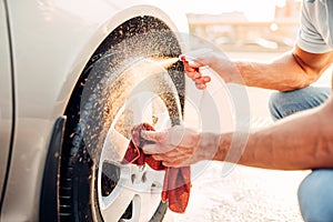 Male hands cleans disk with car rim cleaner