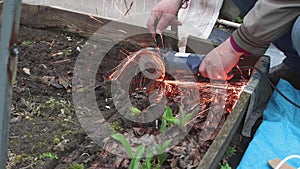 Male hands close-up with a grinder are cutting an old metal structure.