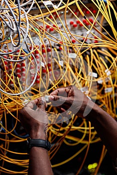 Male hands connecting cables and wires in server room while setting up network