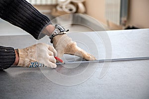 Male hands of  construction worker wearing special gloves measure the details with  construction tape and mark the construction