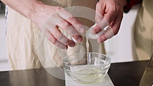 Male hands cracking an egg in a bowl and separating egg white from yolk