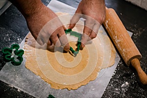 male hands cut out gingerbread cookie in the form of a snowflake, Christmas tree, a man from raw dough on parchment baking paper