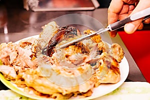 male hands cut a roasted duck with a delicious crust with scissors on a white plate. dish for the festive table