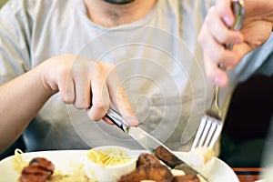 Male hands cutting and eating sausage