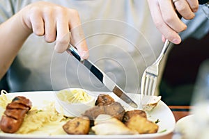 Male hands cutting and eating sausage