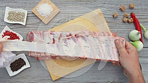 Male hands cutting off the fatty film from the raw ribs for the grill