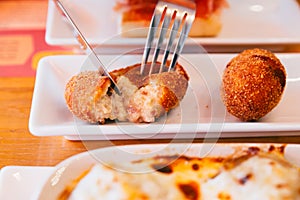 Male hands cutting Papas Rellenas the most popular type of croquettes in Latin American countries with knife and fork photo