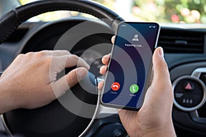 male hands driving car holding phone with incoming call screen