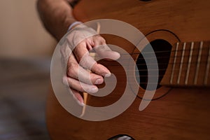male hands of an elderly senior caucasian man holding and playing a classical guitar