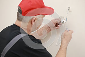 Male hands of electrician installing socket for light bulb