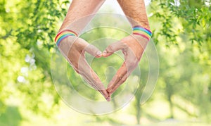 Male hands with gay pride wristbands showing heart