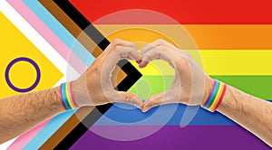 male hands with gay pride wristbands showing heart