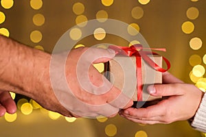Male hands giving Christmas gift box with red bow to kid girl hands