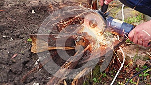 Male hands with a grinder are cutting a rusty destroyed metal structure