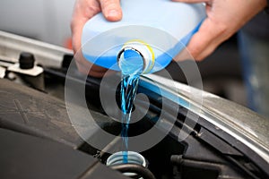 Male hands hold bottle of blue antifreeze in photo