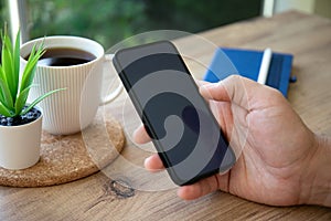 male hands hold phone with black screen background cafe