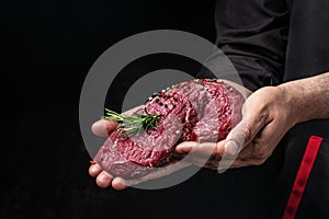 Male hands holding beef meat on a dark background, Whole piece of tenderloin with steaks and spices ready to cook, Long banner