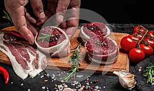 Male hands holding beef meat on a dark background, Whole piece of tenderloin with steaks and spices ready to cook, Long banner