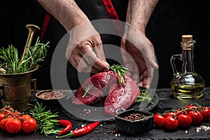Male hands holding beef meat on a dark background, Whole piece of tenderloin with steaks and spices ready to cook, Long banner
