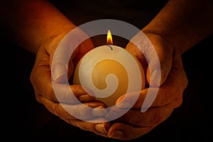 Male hands holding burning candle with flame