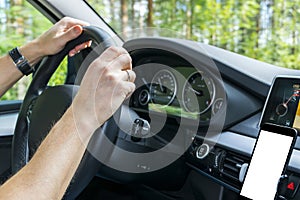 Male hands holding car steering wheel. Hands on steering wheel of a car driving near the lake. Man driving a car inside cabin.
