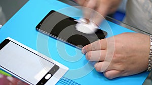 Male Hands holding and cleaning a mobile phone screen to put on, apply a protective tempered glass to Protect a