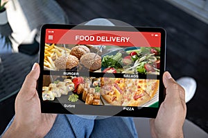 male hands holding computer tablet with app food delivery screen