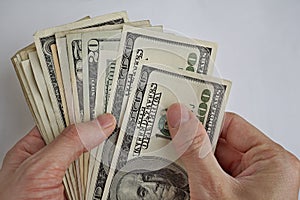 Male hands holding and counting the pile of US Dollars American currency, USD as symbol of business success