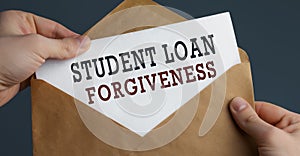 Male hands holding craft envelope with text STUDENT LOAN FORGIVENESS on blue background