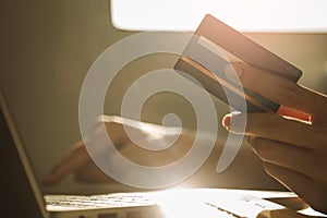 Male hands holding credit card and using laptop computer at working desk for online shopping