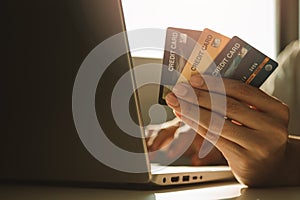 Male hands holding credit cards and using laptop computer at working desk for online shopping while break from work at home