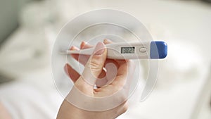 Male hands holding a digital thermometer with high temperature