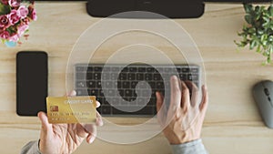 Male hands holding gold credit card making e bank online payment. Man consumer paying for purchase in web store using laptop