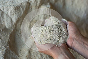 Male hands holding handful of soy flour on background of large pile