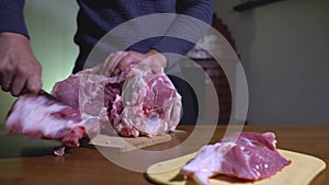 Male Hands Holding Knife and Cutting Meat on the Cutting Board. Cuts Fresh Meat Standing at Table in Domestic Kitchen in